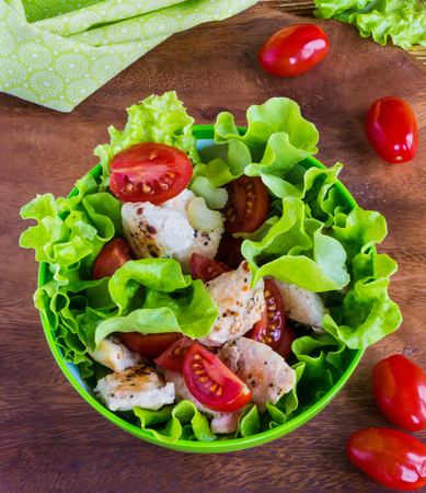 Chicken salad with cherry tomatoes and lettuce on wooden background.の写真素材