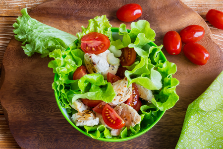 Chicken salad with cherry tomatoes and lettuce on wooden background.の写真素材