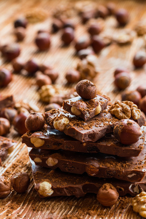 Chocolate and nuts: hazelnuts and walnuts on a wooden background, selective focusの写真素材