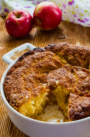 Apple pie in a white baking dish on the wooden background.の写真素材