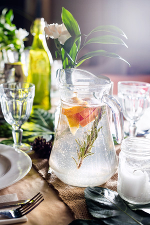 A carafe of fruity beverage with mint and lemon on a decorated table ready for dinner. Beautifully decorated table set for wedding or another event in the restaurantの写真素材
