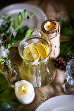 A carafe of fruity beverage with mint and lemon on a decorated table ready for dinner. Beautifully...
