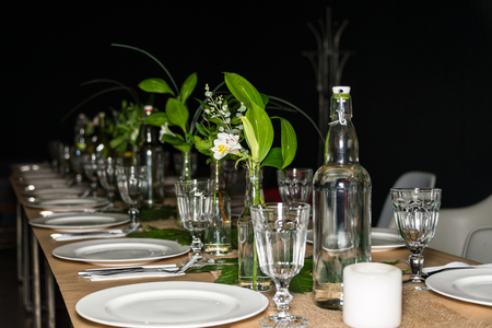 Decorated table ready for dinner. Beautifully decorated table set with flowers, candles, plates and...
