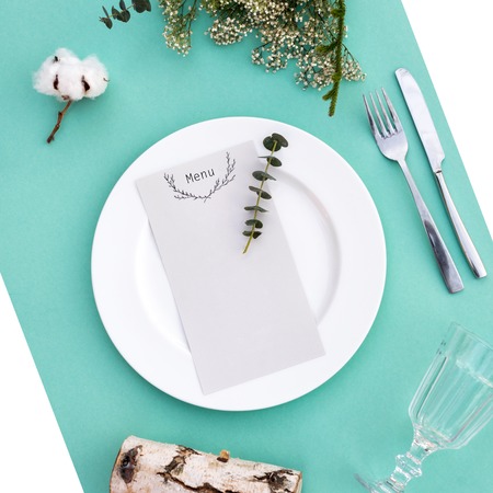 Dinner menu for a wedding or luxury evening meal. Table setting from above. Elegant empty plate, cutlery, glass and flowers.の写真素材