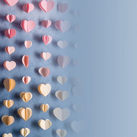 Colorful hearts paper garland hanging on the wall. Romantic Valentine's day background. Instagram style toned photo with copy space for your textの写真素材