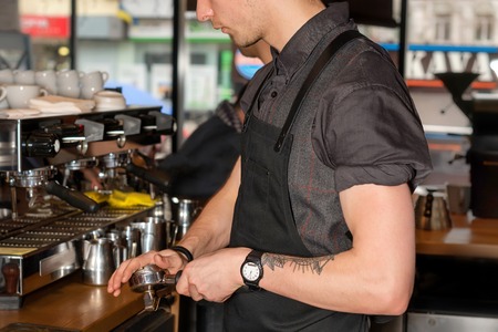 Barista making coffee using press for ground coffee