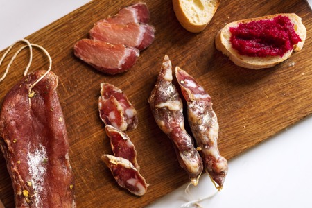 Top view horizontal image of various meats on serving board with ham, pork, beef and homemade bread with beetroot-horseradish spread on rustic wood. Selective focusの写真素材