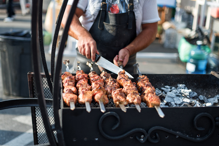 Man cooking, only hands, he is cutting meat or steak for a dish. Delicious grilled meat on grill. Barbecue weekend. Selective focusの写真素材