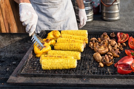 Chef making grilled vegetables outdoor on open kitchen international street food festival eventの写真素材