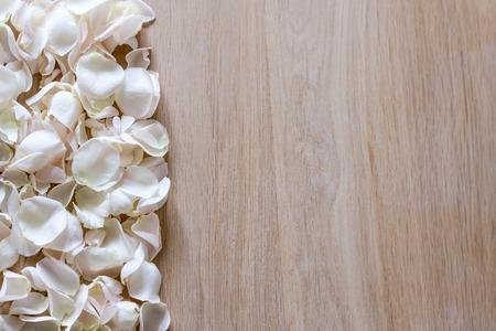 White rose petals on wooden background with space for your textの写真素材