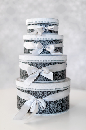 Round celebration gift boxes with silver ribbon bows on white table. Stack of presents in luxury interiorの写真素材