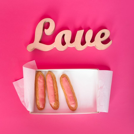 Word love, wooden letters on pink paper with fresh cupcakes. Valentine's day background. Top view. Lovestory or wedding decorの写真素材