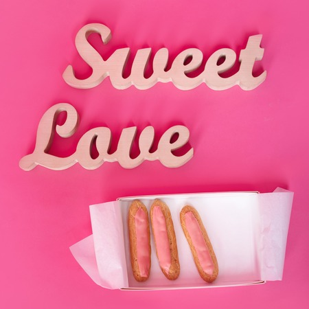Words sweet love, wooden letters on pink paper with open box of fresh cupcakes. Valentine's day background. Lovestory or wedding decorの写真素材