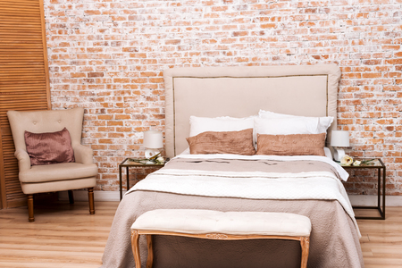 Beautiful loft bedroom with bed and armchair near brick wallの写真素材