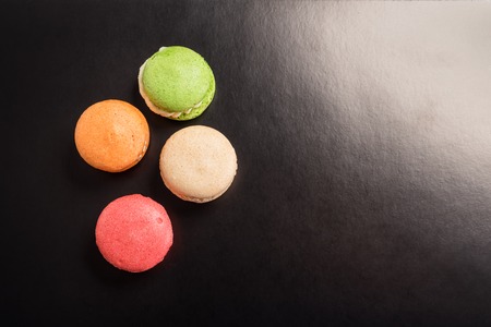 Multicolored macaroons falling or flying isolated on black background. Free space for textの写真素材
