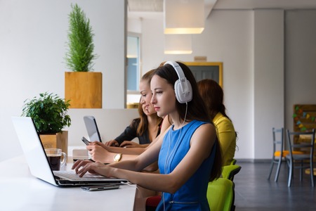 Group of pretty businesswoman working together with new startup project using laptop computer in modern loft. People and teamwork concept - happy creative team in office. Women in businness.の写真素材