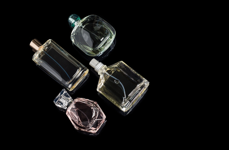 Different perfume bottles with reflections on black background with space for text. Perfumery, cosmetics.の写真素材