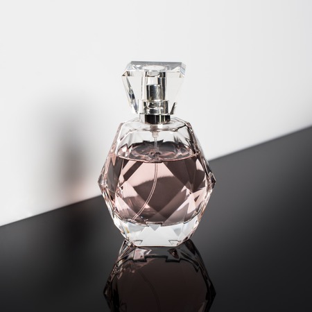 Perfume bottle with reflection on white background. Perfumery, cosmetics.