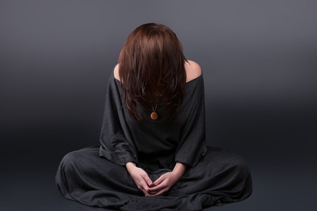 Portrait of a young caucasian woman praying. Prayer girl dressed in Vestments of a nun on gray studio background. Religion and hope conceptの写真素材