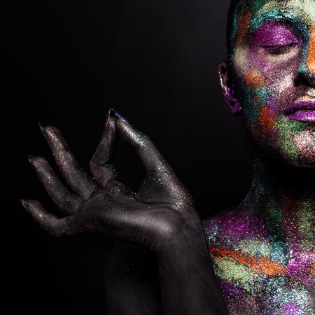 Young artistic woman in black paint and colourful powder. Glowing dark makeup. Creative body art on the theme of space and stars. Bodypainting project: art, beauty, fashion.の写真素材