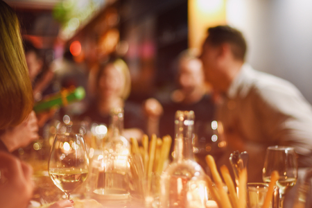 Abstract blurred group of friends meeting in the restaurant. Blurry background of caucasian people having fun, eating and celedrating together. Lifestyle, friendship, party conceptの写真素材