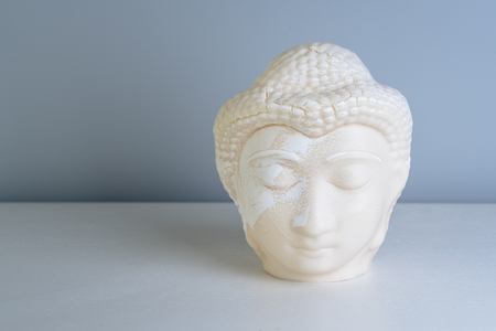 Buddha face. Buddha statue made of white marble with free space for text. Concept of peace, calm and tranquility. Buddhist artifact for Zen style interior decor.の写真素材