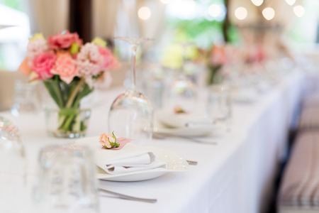 Flower table decorations for holidays and wedding dinner. Table set for holiday, event, party or wedding reception in outdoor restaurant.の写真素材