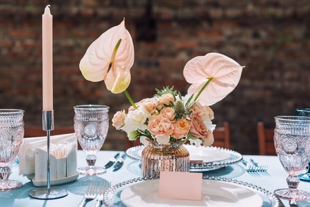 Flower table decorations for holidays and wedding dinner. Table set for holiday, event, party or wedding reception in outdoor restaurant.の写真素材