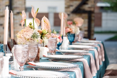 Flower table decorations for holidays and wedding dinner. Table set for holiday, event, party or wedding reception in outdoor restaurant.の写真素材