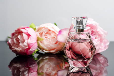 Pink perfume bottle with flowers on black and white background. Perfumery, cosmetics, fragrance collectionの写真素材