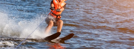 Woman riding water skis closeup. Body parts without a face. Athlete water skiing and having fun. Living a healthy lifestyle and staying active. Water sports theme. Summer by the sea. Banner for websiteの写真素材