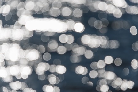 Water bokeh background. Defocused water surface with waves glittering in the sunの写真素材