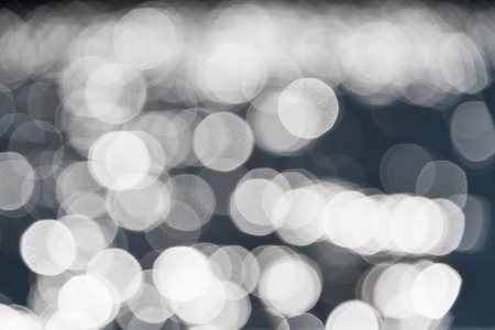Water bokeh background. Defocused water surface with waves glittering in the sunの写真素材