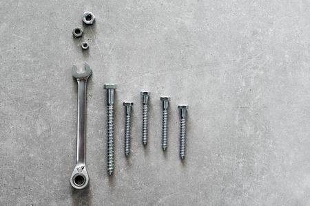 Construction tools. The screws, nuts and bolts on concrete background. Repair, home improvement concept. Space for text, top view, flat lay.の写真素材