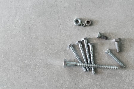 Construction tools. The screws, nuts and bolts on concrete background. Repair, home improvement concept. Top view, flat lay.の写真素材