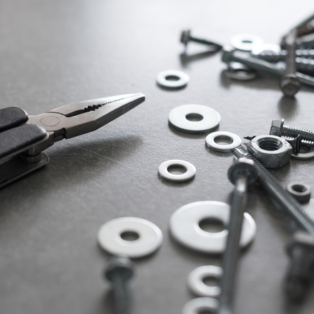Construction tools. The screws, nuts and bolts with pliers on concrete background. Repair, home...