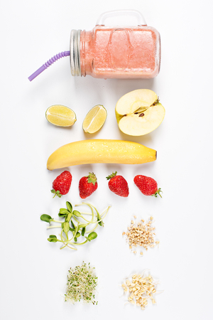 Detox cleanse drink, fruits and berries smoothie ingredients. Natural, organic healthy juice for weight loss diet or fasting day. Mason jar of dietary drink with strawberries, microgreens and bananaの写真素材