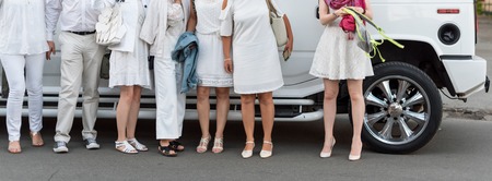 People dressed in white posing next to limousine. Body parts, white partyの写真素材