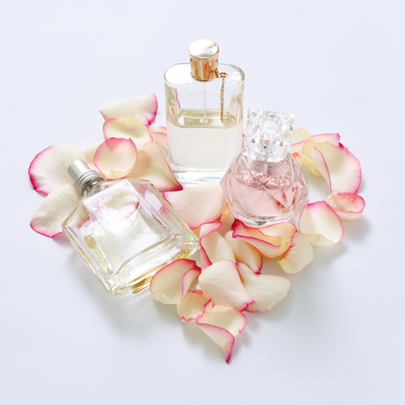 Perfume bottles with flower petals on light background. Perfumery, fragrance collection. Women accessories.の写真素材