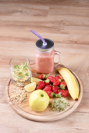 Detox cleanse drink, fruits and berries smoothie ingredients. Natural, organic healthy juice for weight loss diet or fasting day. Mason jar of dietary drink with strawberries, microgreens and bananaの写真素材