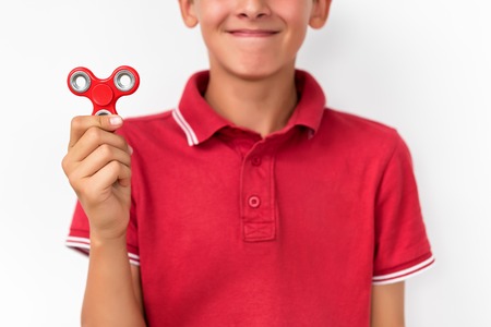 Red hand spinner. Boy playing a popular toy fidget spinner in his hand. Stress relief. Anti stress and relaxation adhd attention fad boy concept.の写真素材