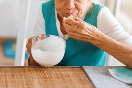 Senior woman hands holding big cup of yogurt. Old woman holding a glass of milk, health care concept, wrinkled skin, no face. Soft focus.の写真素材