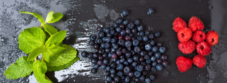 Fresh washed raspberries, blueberries, mint leaves with waterdrops. Organic berries on grey slate stone board. Smoothie ingredients. Banner for website.の写真素材