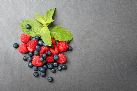 Fresh washed raspberries, blueberries and mint leaves. Organic berries on grey slate stone board. Top view, space for text.の写真素材
