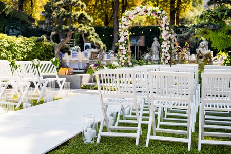 Wedding arch with flowers outdoors. Beautiful wedding set up. Wedding ceremony in the garden with sculptures and fountain. Part of the festive decor, floral arrangement.の写真素材