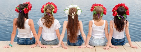 Back view of five young ladies, wearing flower wreaths, jeans and white tshirts. Group of friends...
