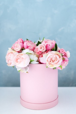 Flowers in round luxury present box. Bouquet of pink and white peonies in paper box. Mock-up of hat box of flowers with free copyspace for text. Interior decoration in in pastel colors.の写真素材