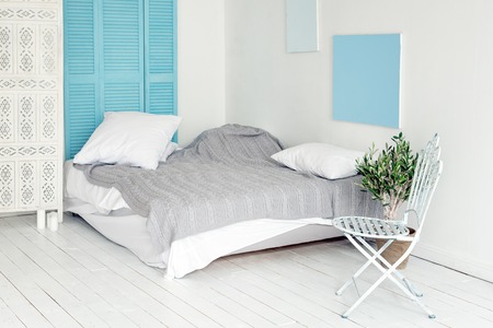 White loft interior in scandinavian style. Cozy area of apartment in nordic style, bedroom with white wood flooring, metal chair and olive tree. Room makeover concept, free space for text.の写真素材