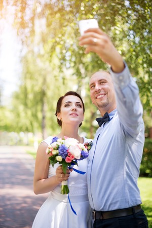 Happy wedding couple - bride and groom making selfie during wedding ceremony outdoors.の写真素材