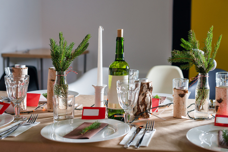 Decorated Christmas holiday table ready for dinner. Beautifully decorated table set with candles, spruce twigs, plates and serviettes for event in the restaurantの写真素材